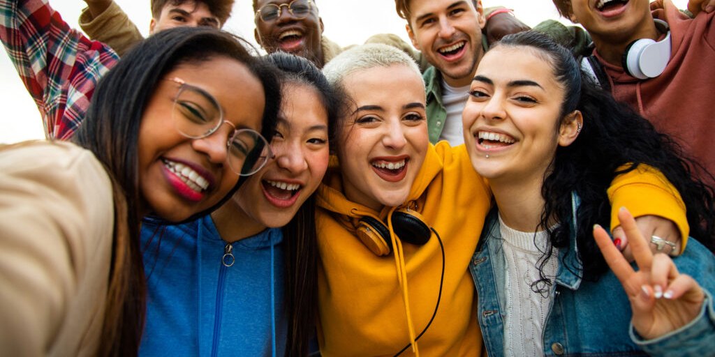 A group of young people crowded together for a selfie, laughing.